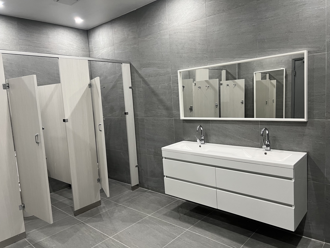 Commercial washroom renovation with partitions and double vanity by Kodiak Construction Group